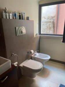 een badkamer met een toilet, een wastafel en een raam bij Guest House Isabel Pinto in Bisceglie