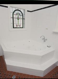 a white bathroom with a tub and a stained glass window at Clare Valley Heritage Retreat in Clare