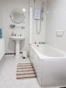 a white bathroom with a sink and a tub and a toilet at Mellte Avenue - Waterfalls House in Pont-Nedd-Fechan