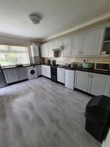 a large kitchen with white cabinets and a wooden floor at Mellte Avenue - Waterfalls House in Pont-Nedd-Fechan