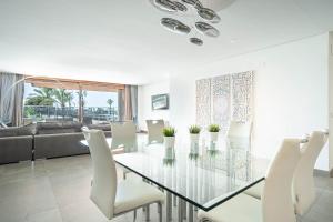 sala de estar con mesa de cristal y sillas blancas en GRAND TERRACE APARTMENT in Puerto de Alcudia, en Alcudia