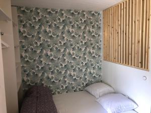 a bedroom with a wall with a flower wallpaper at Appart au cœur de la ville (vue montagne) in Cauterets