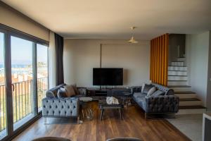 een woonkamer met 2 banken en een televisie bij Duplex Loft mit Panorama Seaview in Kuşadası
