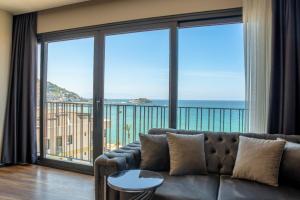 uma sala de estar com um sofá e janelas grandes em Duplex Loft mit Panorama Seaview em Kusadası