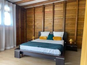 a bedroom with a bed with a wooden wall at Gites de la vallée in Le Gosier