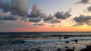 a sunset over the ocean with rocks in the water at San Giuseppe Casa per Ferie in Quercianella