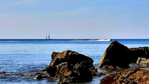 a sail boat in the ocean with rocks in the water at San Giuseppe Casa per Ferie in Quercianella