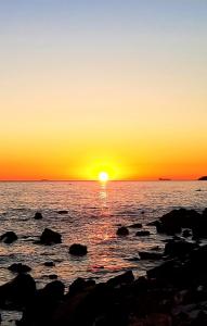 a sunset over a body of water with rocks at San Giuseppe Casa per Ferie in Quercianella