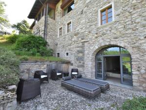 een stenen gebouw met een patio met stoelen en een bank bij Apartment Maso Dolcevista by Interhome in Lundo