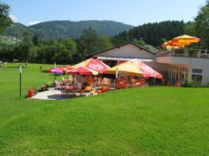 a group of people sitting under umbrellas outside of a building at Apartment Frank-2 by Interhome in Feldkirchen in Kärnten