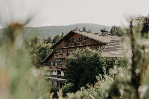 a large wooden house in the middle of a forest at Hôtel Les Roches Fleuries in Cordon