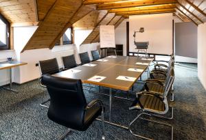 einen Konferenzraum mit einem langen Tisch und Stühlen in der Unterkunft Hotel Simonshof in Wolfsburg