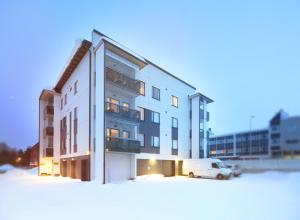 ein weißes Gebäude mit einem Van davor in der Unterkunft First Aparthotel Dasher in Rovaniemi