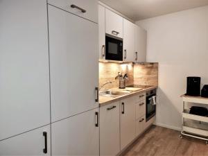 een keuken met witte kasten en een wastafel bij Steiner Strandappartements Appartement 306 Süd- Landseite in Stein