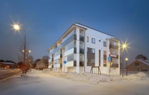 a white building on a snowy street at night at First Aparthotel Dasher in Rovaniemi