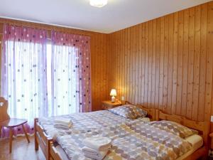 ein Schlafzimmer mit einem Bett und einem großen Fenster in der Unterkunft Chalet Moulinettes N- 8 by Interhome in Bluche