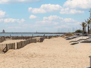 una playa de arena con una valla y el océano en Apartment Du Soleil-3 by Interhome, en La Grande-Motte