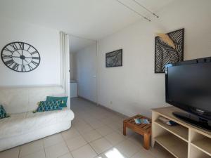 a living room with a couch and a clock on the wall at Apartment Les Maisons de l'Océan-9 by Interhome in Lacanau-Océan