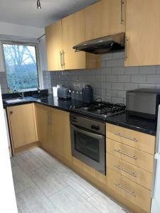 a kitchen with wooden cabinets and a stove top oven at Lovely one bedroom apartment in Thornton Heath