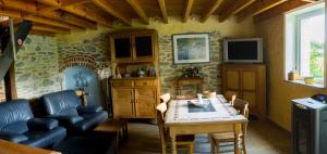 a living room with a table and a tv at Gîte « le Sault-Poket » in Walcourt