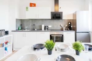 a kitchen with white cabinets and a table with plants at Chic City-View Apartments in Hanau in Hanau am Main