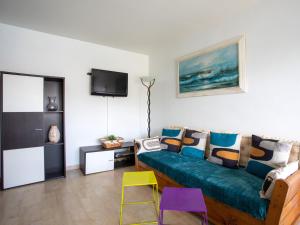 a living room with a blue couch and colorful stools at Apartment La Pinède-2 by Interhome in Puits