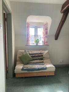 a bed in a room with a window and a couch at Delightful Pretty Cottage in Banbury