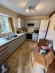 uma cozinha com armários brancos, uma mesa e um frigorífico em Delightful Pretty Cottage em Banbury