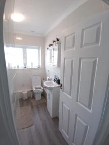 a bathroom with a toilet and a sink and a door at Exquisite Two Bed Apartment in Grays - Free Wi-Fi and Netflix in Stifford