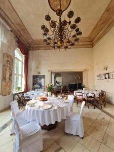 a dining room with white tables and chairs and a chandelier at Dwór Podstolice - House of Rosenthal in Podstolice