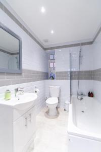 The Pearl Suite by Margate Suites في مارغايْت: حمام ابيض مع مرحاض ومغسلة وحوض استحمام