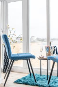The Pearl Suite by Margate Suites في مارغايْت: كرسيان زرقان وطاولة أمام النافذة
