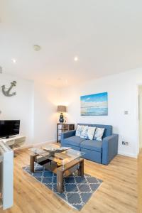 a living room with a blue couch and a coffee table at The Pearl Suite by Margate Suites in Margate