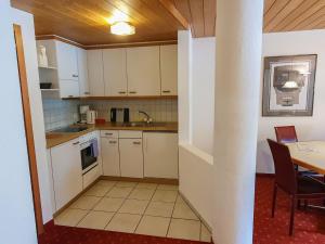 eine kleine Küche mit weißen Schränken und einem Tisch in der Unterkunft Apartment Chalet Abendrot-15 by Interhome in Grindelwald