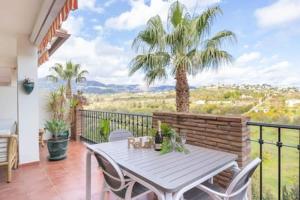 une table et des chaises sur un balcon avec un palmier dans l'établissement Fairway Apartman Mijas Golf 2 - Limonar, à Santa Fe de los Boliches