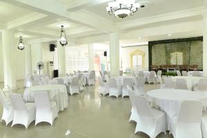 a banquet hall with white tables and white chairs at MCM HOTEL WISATA BOJONEGORO in Bojonegoro