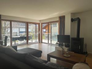 sala de estar con sofá, TV y balcón en Wunderschöne Wohnung am See mit Sauna & Whirlpool en Unterterzen