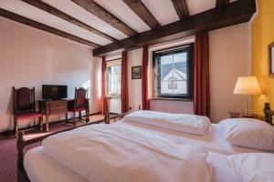 Un dormitorio con una gran cama blanca y una ventana en Hotel Bären en Feldkirch