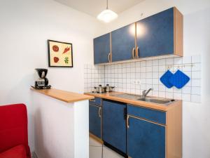 una pequeña cocina con armarios azules y fregadero en Apartment Kiefernweg by Interhome, en Ramersbach