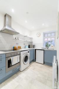 a kitchen with blue cabinets and a washer and dryer at The Pearl Suite by Margate Suites in Margate