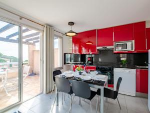 a kitchen with red cabinets and a table with chairs at Apartment Les Coteaux de la Nartelle-17 by Interhome in Sainte-Maxime