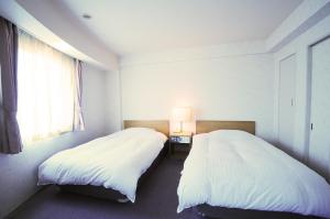 
a bedroom with two beds and a lamp at Hotel Saharin in Wakkanai
