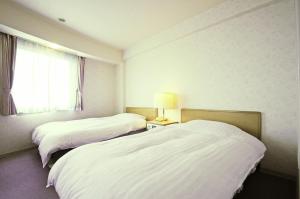 ein Hotelzimmer mit 2 Betten und einem Fenster in der Unterkunft Hotel Saharin in Wakkanai