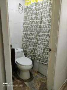 baño con aseo y pared de azulejos blancos en Santa Teresa Hostel en Temuco