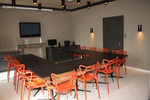 a conference room with a black table and orange chairs at Maison Marie Barrault in Les Herbiers
