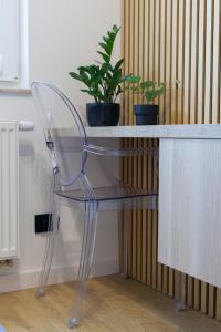 a clear chair sitting in front of a desk with plants at Butterfly Apartment with Parking by Renters in Gdańsk