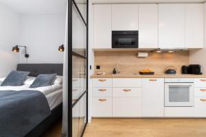 um quarto com uma cama e uma cozinha com armários brancos em Butterfly Apartment with Parking by Renters em Gdańsk