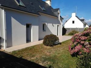 a white house with a driveway and a yard at La maison des vacances in Trégunc