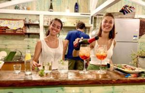 dos mujeres de pie en un mostrador vertiendo vino en copas en HAPPY GLAMPING MADONIE en Polizzi Generosa