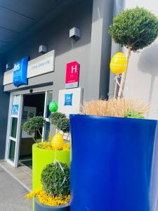 uma frente de loja com vasos de árvores em frente em ibis Budget Colmar Centre Gare em Colmar